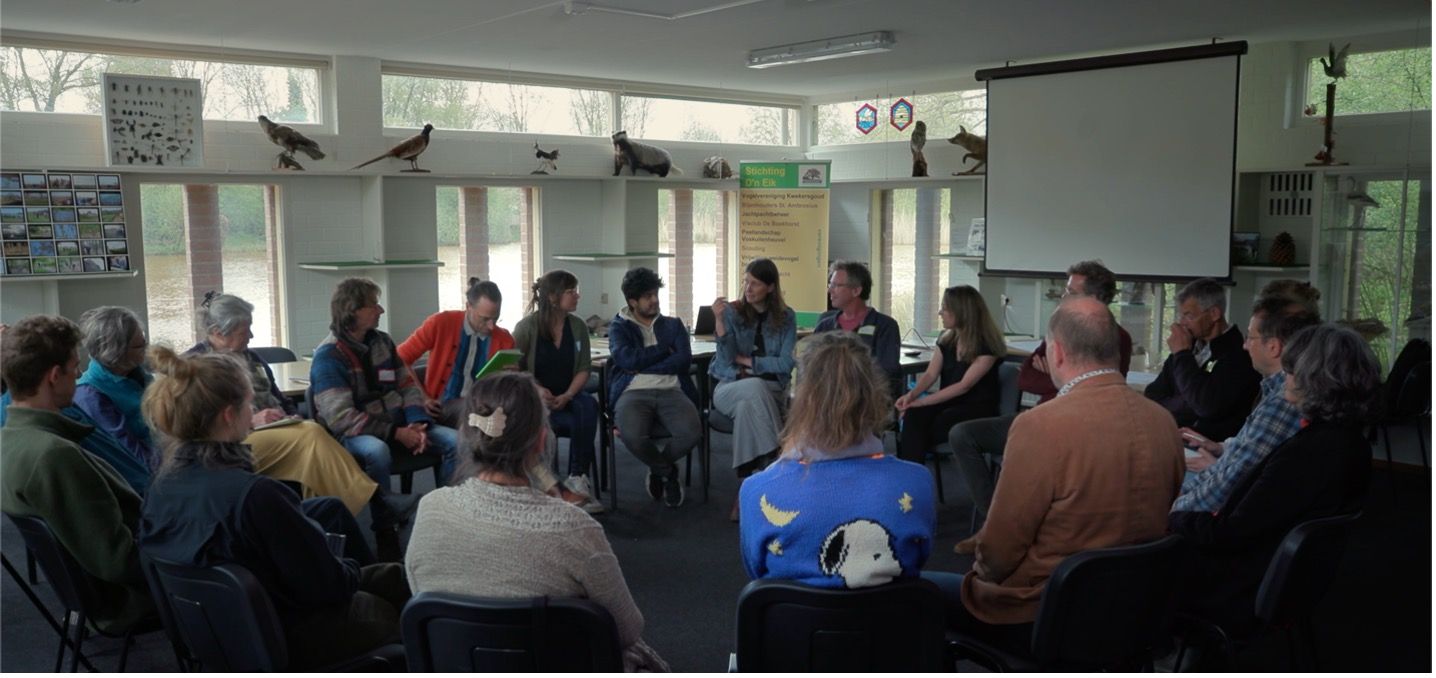 Imagen de la película Smart Forests que muestra a los participantes de la escuela de campo debatiendo planes y prácticas de biodiversidad en Ecodorp Boekel. Países Bajos. Mind the Film junto con Smart Forests, 2025.